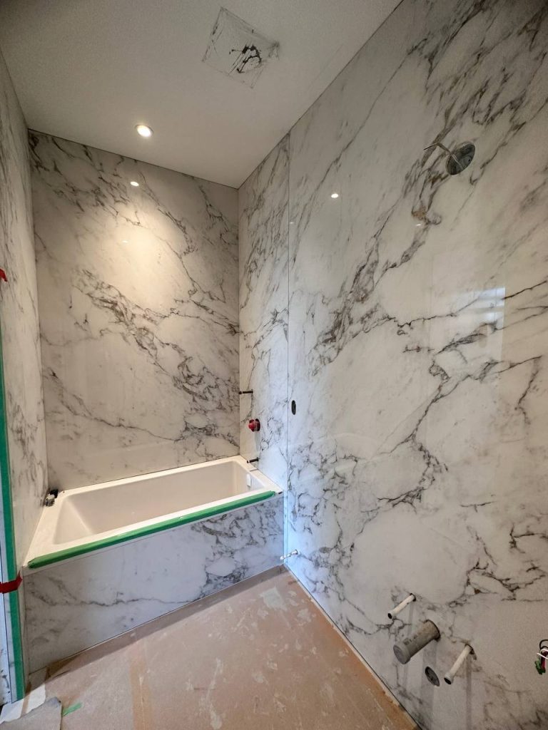 Large-format marble-look porcelain bathroom wall installation